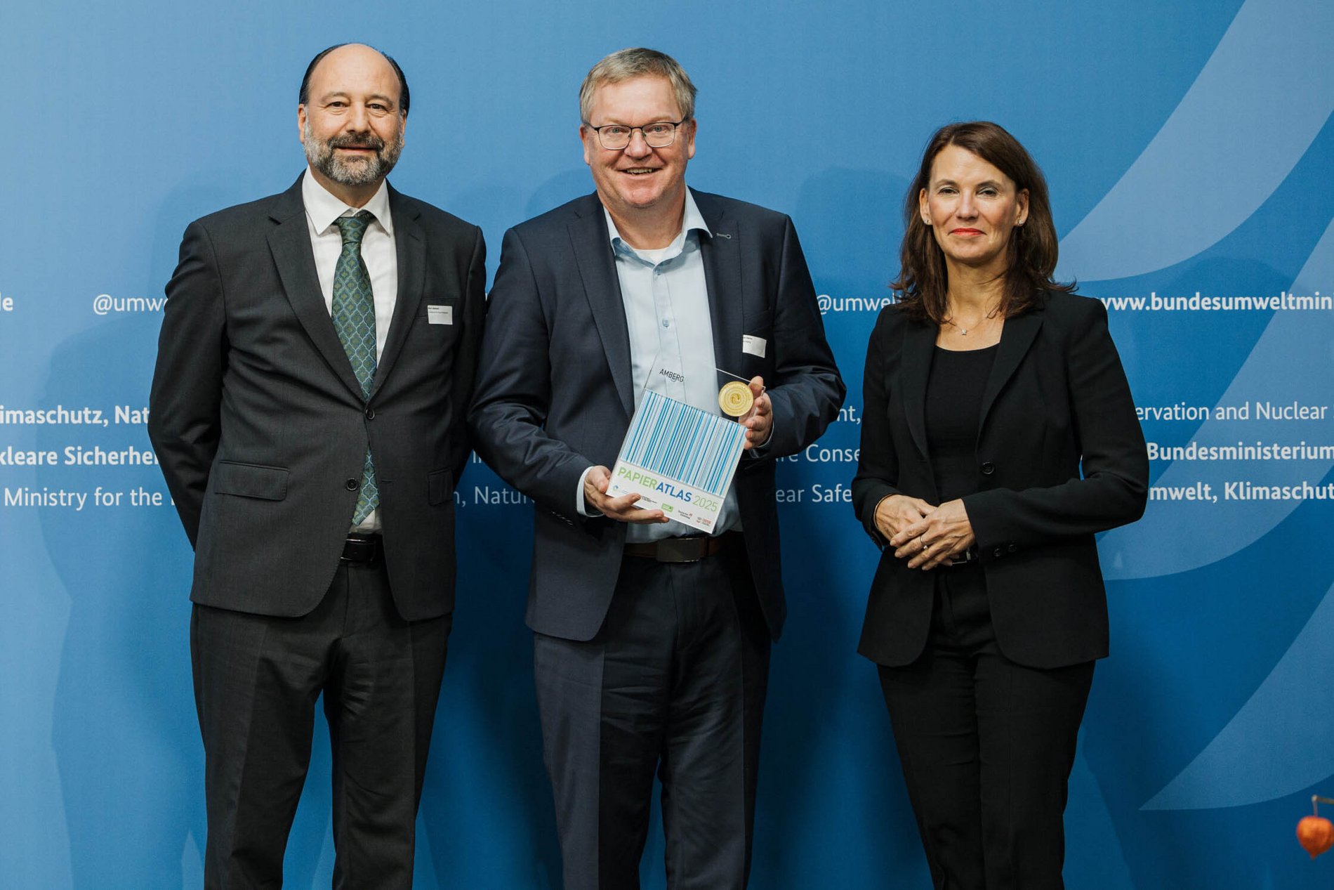 Das Foto zeigt die Übergabe der Auszeichnung an die Stadt Amberg als „Recyclingpapierfreundlichste Mittelstadt“ 2025 mit Marc Gebauer (Sprecher der Initiative Pro Recyclingpapier), Michael Cerny (Oberbürgermeister der Stadt Amberg), Parlamentarische Staatssekretärin Rita Schwarzelühr-Sutter.